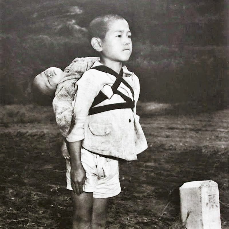 Junge nach dem Atombombenabwurf über Nagasaki, 1945. Das Baby auf seinem Rücken ist bereits gestorben. Er wartet am Krematorium.